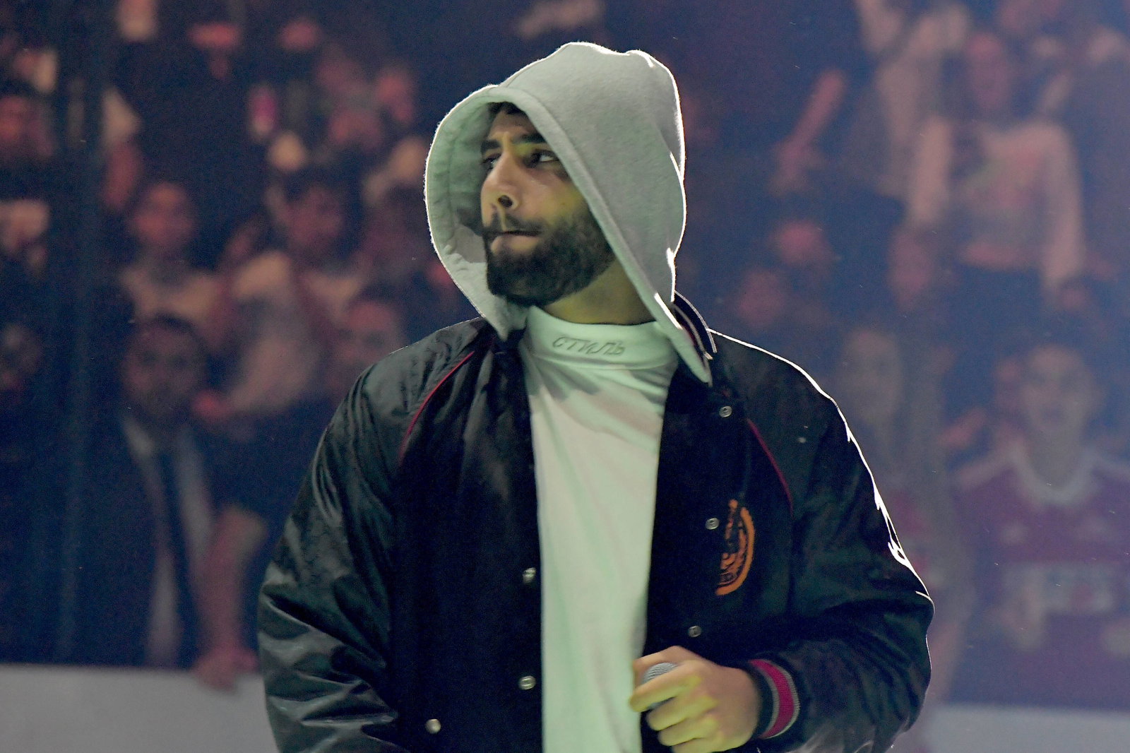 rapper samra steht auf bühne mit kapuze auf und bomberjacke 